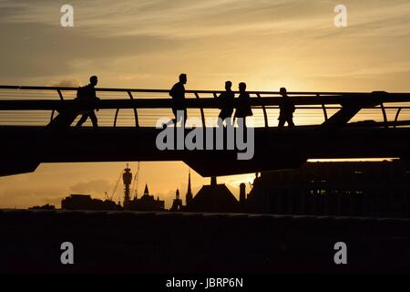 London, UK. 12th June 2017. People are silhouetted as the sun sets behind the Millennium Bridge in London, UK. The BT tower is visible in the skyline beyond. Credit: Patricia Phillips/Alamy live news Stock Photo