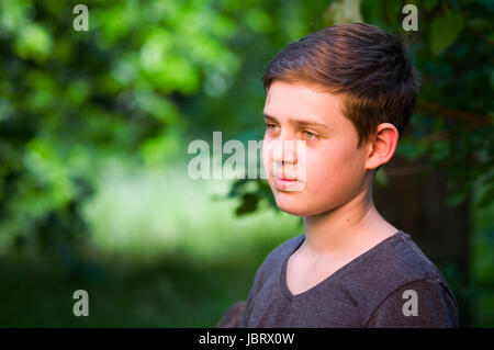 seitliches Outdoor-Kopf-und-Schulter-Porträt eines 13jährigen männlichen Teenagers zufrieden zur Seite blickend Stock Photo