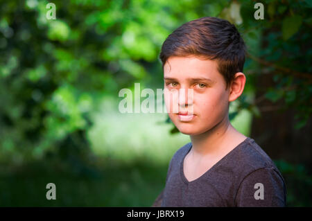 seitliches Outdoor-Kopf-und-Schulter-Porträt eines 13jährigen männlichen Teenagers freundlich in die Kamera blickend Stock Photo