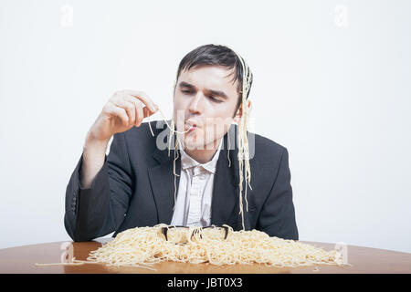 Indulgence and consumerism concept. Gluttonous businessman eating pasta. Stock Photo