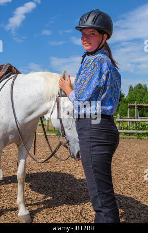Junge Frau streichelt weisses Pferd Stock Photo