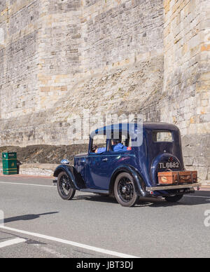 CAERNARFON, WALES - 29 SEPTEMBER 2013: Vintage classic car taking part in the Walled Towns Trail Car Run 2013 passes the walls of Caernarfon Castle en route to its next destination Stock Photo