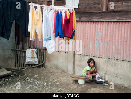 AGADA, PHILIPPINES - MARCH 23, 2012: Girl washing clothes in the small village in Philippines. About 12 per cent of Philippines children between the ages of five and 14 are forced to work. Stock Photo