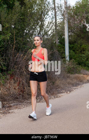 attraktive sportliche junge Frau beim Joggen auf einer Straße im Freien bei Tageslicht Stock Photo