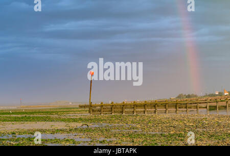 Rainbow in the sky over the beach at low tide. Stock Photo
