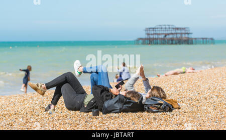 Young women laying on a beach using smartphones. Stock Photo
