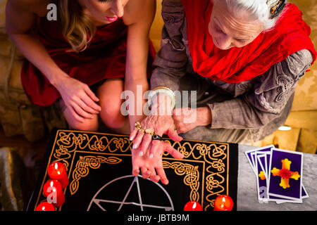 Female Fortuneteller or esoteric Oracle, sees in the future by hand reading during a Seance to interpret them and to answer questions Stock Photo