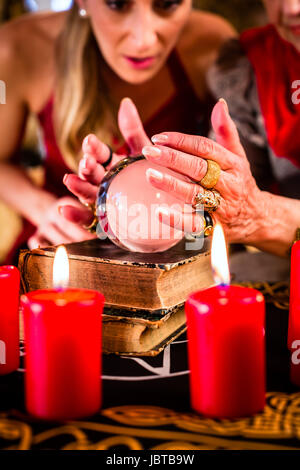 Female Fortuneteller or esoteric Oracle, sees in the future by looking into their crystal ball during a Seance to interpret them and to answer questions Stock Photo