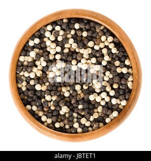 Black and white pepper in wooden bowl. Also called Mignonette pepper. Peppercorns, dried berries of Piper nigrum. Spice and seasoning. Stock Photo