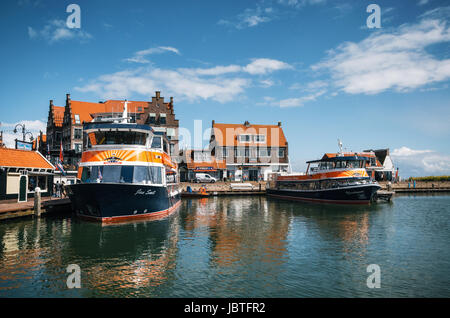 Volendam, Netherlands - 26 April, 2017: Harbor of Volendam with colorful tourist boats and promenade at sunny day, Netherlands. Volendam is a popular  Stock Photo