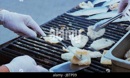 The chef toils over an open grill frying fish, rapans and squid. Cooking mackerel fillet at grill for fish durum. In-ground barbecue with fish grillin Stock Photo