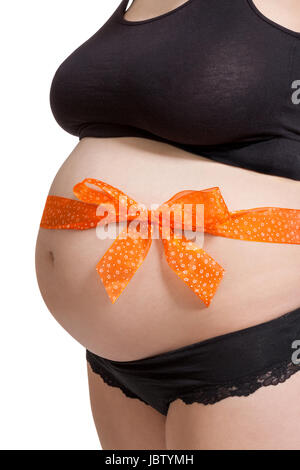 Junge schwangere Frau mit orangener Schleife um den Bauch als Nahaufnahme isoliert vor weißem Hintergrund Stock Photo
