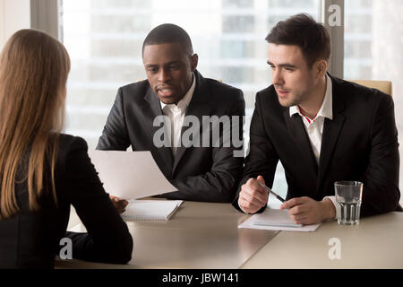 Multiracial black and white recruiters, executive hr management group interviewing female job applicant, headhunters studying cv resume of candidate,  Stock Photo