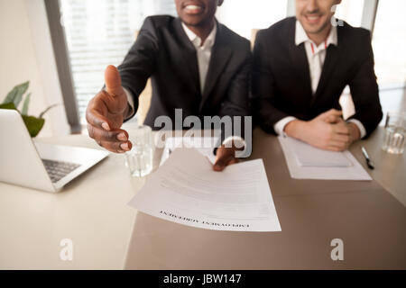 Close up of black businessman offering job, reaching out employment agreement to successful applicant, labor contract of work, extending hand for hand Stock Photo