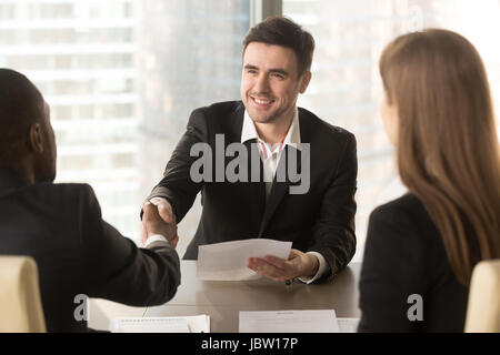 Happy applicant greeting employers at job interview, cheerful satisfied partners shaking hands, making deal agreement with friendly handshake at meeti Stock Photo