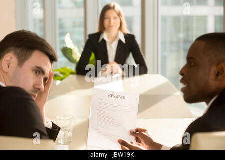 Funny multiethnic employers impressed by female applicant skills at job interview, black and white recruiters considering candidate shocked by great c Stock Photo
