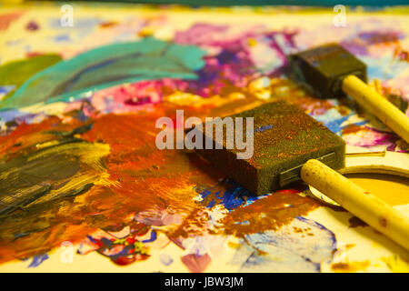 Artiste painting with sponge brushes deposited on canvas. A moment of inspiration. Stock Photo