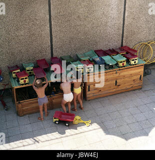 Rostock, GDR, children pick up toys from a crate in the kindergarten Stock Photo