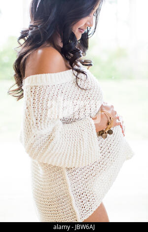 Pregnant woman holding stomach, smiling Stock Photo