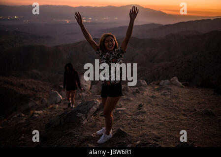 Portrait of young woman with hands raised in Joshua Tree National Park at sunset, California, USA Stock Photo