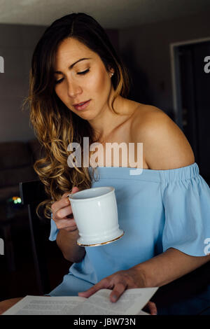 Young woman reading book at table Stock Photo