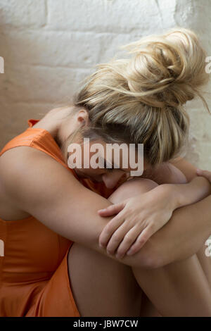 Miserable young woman sitting down Stock Photo