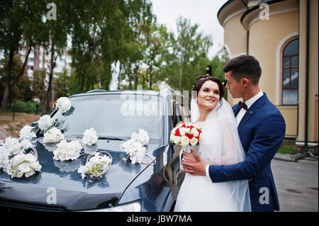 Wedding couple standing outside next to the cool decorated car looking at each other in the eyes. Stock Photo