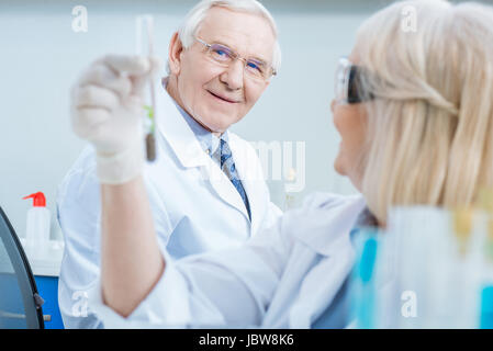 senior man scientist looking at test tube in colleague hand Stock Photo