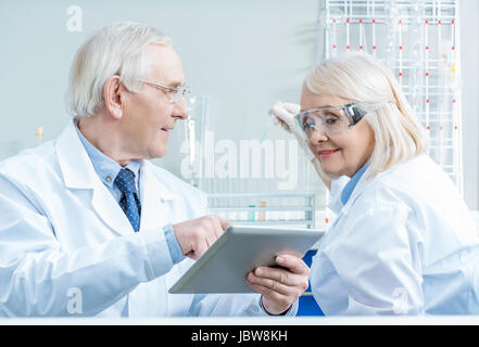 Senior couple of scientists working with digital tablet in lab Stock Photo