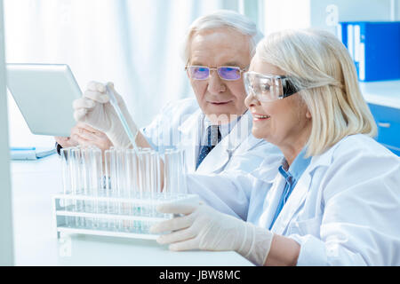 Smiling senior chemists working with test tubes in laboratory Stock Photo