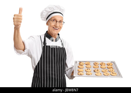 Baker holding a tray with freshly baked cookies and making a thumb up sign isolated on white background Stock Photo