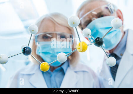 Chemists in protective workwear looking at molecular model Stock Photo