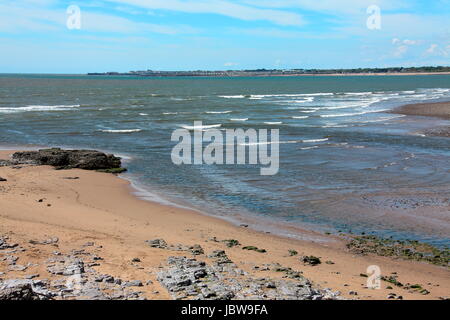 A view across the mouth of the River Ogmore looking out towards the town of Porthcawl with sandy beaches and blue waters. Stock Photo