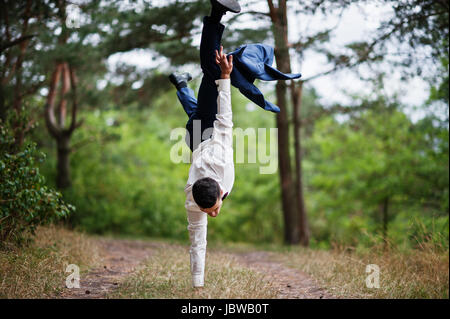 Crazy groom performing tricks on his wedding day in the middle of pine forest. Stock Photo