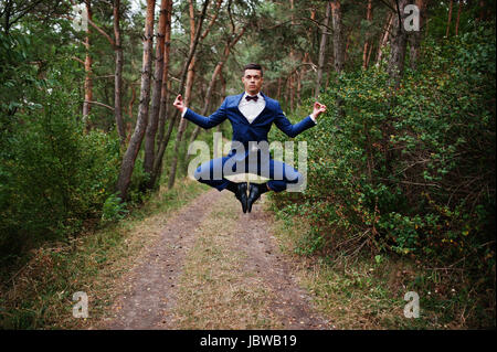 Crazy groom performing tricks on his wedding day in the middle of pine forest. Stock Photo