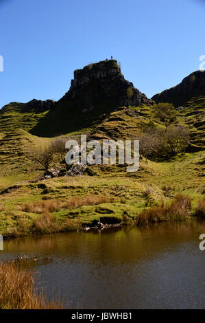 Two People on the Rocky Tower of Castle Ewen & the Cone Shaped Hillocks in Fairy Glen near Uig, Isle of Skye,North West Scottish Highlands,Scotland. Stock Photo