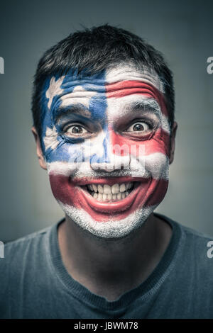 Portrait of funny toothy smiling man with US flag painted on face. Stock Photo