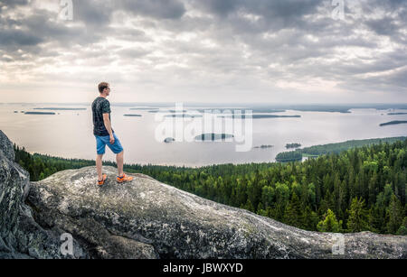Scenic landscape with lake and sunset at evening in Koli, national park. Finland. Hiker standing in the front. Stock Photo