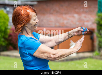 Elderly lady playing with a fidget spinner, the latest stress relieving craze Stock Photo