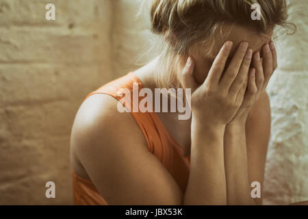 Close up of a sad young woman hiding face with hands crying