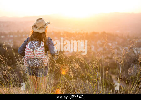 Woman hiking, wearing stars and stripes backpack, rear view Stock Photo