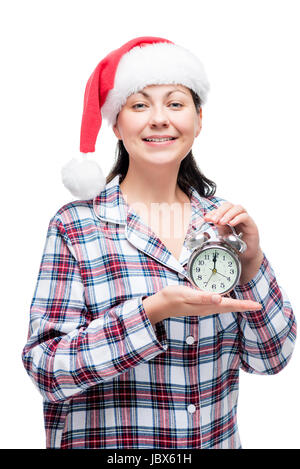 Beautiful girl meets New Year in pajamas with an alarm clock in her hands, a red cap on her head Stock Photo