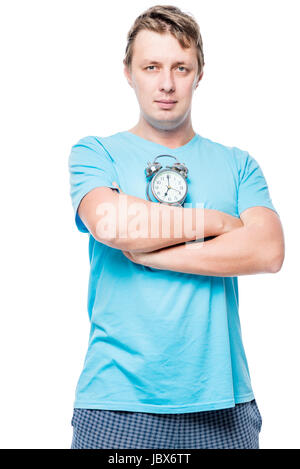 Vertical portrait of a man in pajamas with an alarm clock on white background Stock Photo