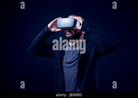 Young hipster bearded man wearing virtual reality goggles. Black background studio VR concept. Stock Photo