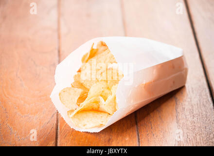 Potato chips in paper pack on wood table Stock Photo