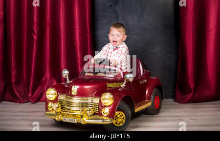 Studio image of cute baby posing in big toy car at studio Stock Photo