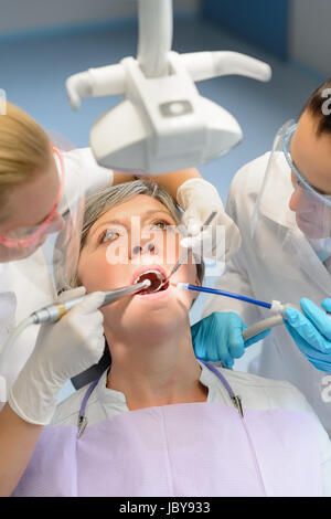 Elderly woman patient open mouth dental checkup professional dentist team Stock Photo
