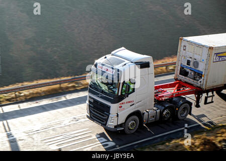 Volvo truck pulling a container trailer climbs the Woodhead PAss on the Yorkshire side Stock Photo