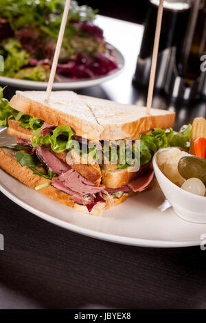 Leckeres sandwich clubsandwich mit bacon schinken käse und ein mit mixed pickels auf einem Teller Stock Photo