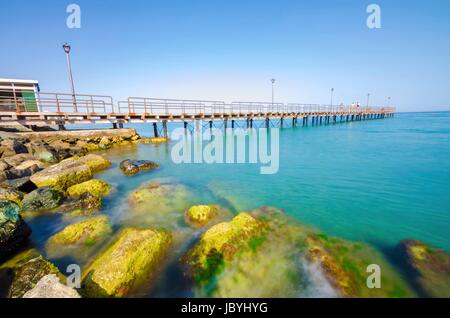 The Limassol pier in Enaerios Area in Cyprus. A day view of the Mediterranean sea, the rocks on the coast of Limassol city and a local coffee shop. Stock Photo